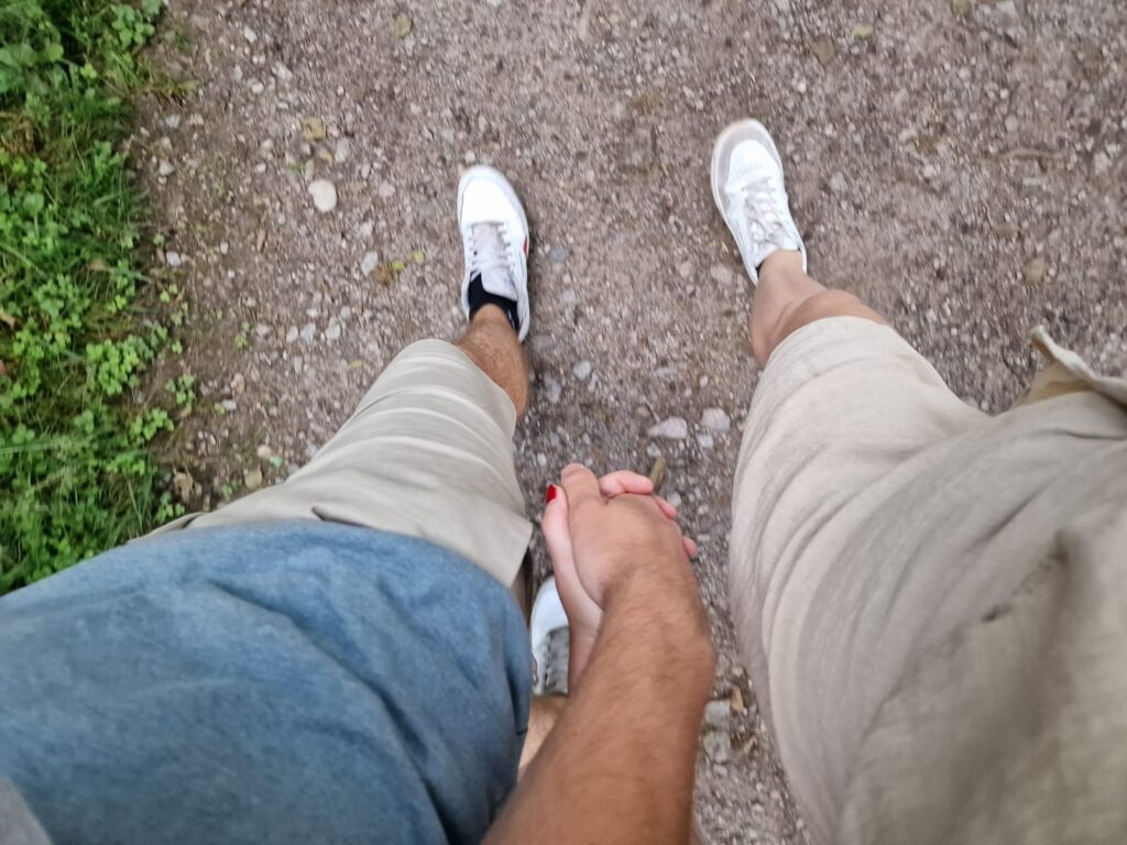 Twee mensen wandelen hand in hand over een grindpad, van bovenaf gezien